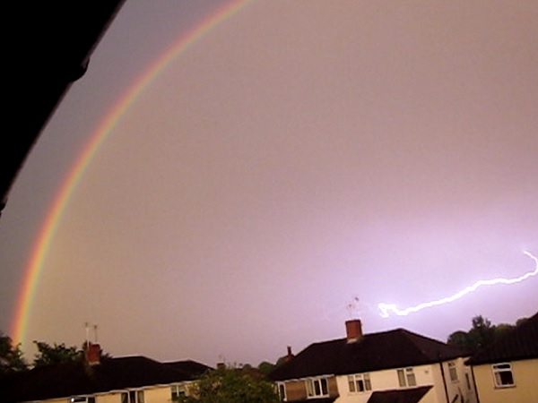 A rainbow and lightning illuminate the sky